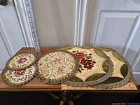 Five vintage doilies arranged side by side on a wooden surface with measuring rulers for scale.