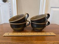 Four handmade speckled pottery mugs stacked two by two, showing overall size and shape with ruler for scale.