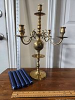 Front view of brass candelabra with blue candles lying on table.