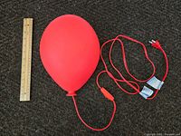 Red balloon-shaped wall lamp alongside a ruler showing size