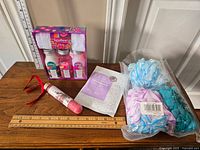 Overview of bath and beauty care lot with all items laid out on a table including the bath set, poufs, mask, bath salts, and bath bomb