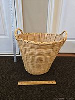 Front view of the large round wicker basket with handles, showing size relative to ruler.
