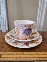 Teacup, saucer, and dessert plate stacked, showing teddy bear designs decorated around each item.