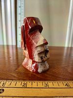 Photo of small marble Moai statue on a wooden surface with ruler for scale showing front and left side profile