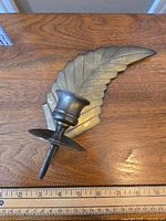 Top-down view of solid brass candle sconce on a wooden surface, highlighting the leaf design and candle holder.