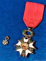 Large and miniature Legion d'Honneur medals displayed on blue background