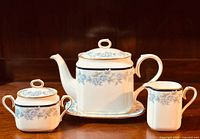 Full set view showing teapot with lid and underplate, creamer, and sugar bowl with lid all decorated with Noritake Bellefonte floral pattern and gold trim.