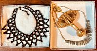 Photo showing the old black glass mourning necklace alongside the gold-filled bottle pendant and the modernist rhinestone necklace, displayed in two white boxes.