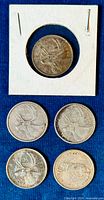 Five circulated Canadian silver quarters on a blue background, one in a cardboard holder stamped 1943, others showing varying degrees of wear.