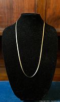 Front view of vintage sterling silver herringbone necklace displayed on black velvet stand, showing full length and design.