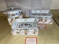 Set of 5 pieces including 3 round casserole dishes with lids and 2 rectangular baking dishes, all with floral Spring Night pattern by Sadek. Original packaging visible.