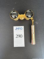 Top view of antique opera glasses showing dual lenses and mother-of-pearl handle folded down.