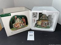 The collectible building figurine in original box with protective styrofoam and wrapping.