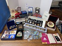 Overview of entire lot on table showing pins, boxes, snow globe, figurines, map brochure
