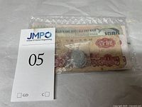 Plastic bag with a stack of bank notes and few coins inside, marked with lot tag 05