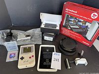 Full lot showing all items including Game Boy, Samsung tablet, T-Mobile hotspots, Jabra speaker, Dynadock docking station, Sony camera, and accessories