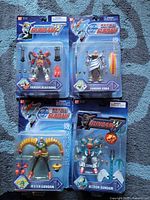 Front view of four unopened blister-packaged Bandai Gundam action figures (Heavyarms, Zebra, Jester, Altron)
