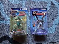 Front view of the two Bandai Gundam Wing action figures Mermaid Gundam and Gundam Deathscythe in sealed blister packs showing figure details and packaging artwork.