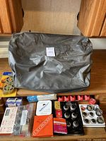 Vinyl plastic cover at back with assorted typeballs in trays, multiple ribbon spools, cleaning solutions and typing accessories laid out on surface