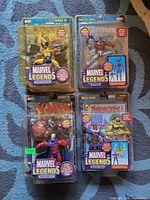 Front view of four unopened Marvel Legends action figures: Wolverine, Deathlok, Magneto, Baron Zemo in original packaging.