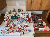 Full view of the collection of Snoopy and Peanuts themed holiday ornaments displayed on a table with some boxes visible.