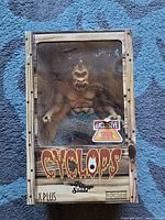 Front view of unopened Cyclops figurine in original box with Tower Records exclusive sticker and wood plank design.