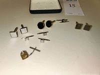 Image showing a total of eight items including three pairs of cuff links and one pair of shirt buttons with chain. Variations in shape: square and round cuff links are visible.