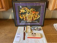 Framed Disney California Adventure pin with layered Disney characters and landmarks. Below, the wristwatch with original tin, sleeve, and box on white cloth.