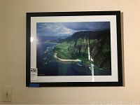 Overall view of the framed signed coastal landscape print on the wall, showing size and framing.