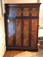 Front view of solid wood computer hutch with decorative veneer panels and four folding doors closed.