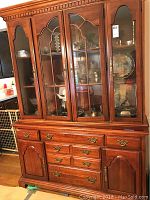 Full front view of wooden china hutch showing top and base sections
