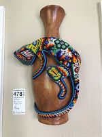 Front view of wooden vase with colorful beaded lizard detail.