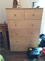 Front view of the dresser showing all six drawers with round wooden knobs and natural wood finish.
