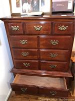 Front view of the solid wood dresser showing six drawers with brass handles, three smaller drawers on top and three larger below, including one drawer opened to reveal interior wood finish.