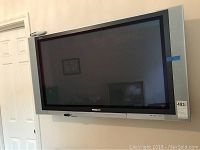 Front wide shot of 42 inch Panasonic Viera flat screen TV mounted on wall, showing overall condition and remote atop TV.