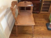 Side view of vintage wooden telephone table with chair attached, showing design and turned legs