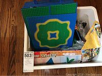 Full view of white plastic bin packed with large Lego base plates, instruction set, and assorted parts