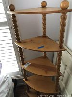 Full view of the wooden corner shelf showing five tiered triangular shelves supported by four twisted spiral spindles and round wooden finials on top corners.
