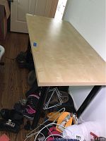Workbench table with a smooth light wood rectangular butcher block style top and black metal legs, showing overall good condition.