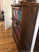 Side angle showing shelves filled with books and wooden side panel showing wood grain.