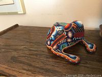 Ceramic frog figurine showing side profile with detailed colorful beadwork