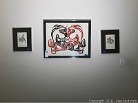 Photo showing three framed prints hanging on the wall: one large center print by Patric Amos and two smaller prints by Bill Reid on either side.