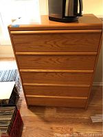 Front view of the wooden dresser showing five drawers and natural wood grain finish.
