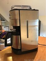 Front and side view of Cuisinart coffee maker with stainless steel finish and insulated carafe on a wooden table.
