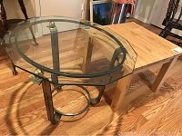 Round glass-top table with heavy metal base; the glass top is beveled and the metal base has circular design elements.