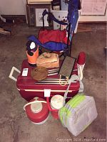 Overview of camping gear including red Igloo cooler, thermoses, lunch sack, folding chair, cups, and water jug.