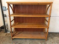 Front view of the bamboo bookshelf showing all four shelves and bamboo frame.