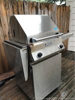 Front angle view of stainless steel Ducane grill showing closed lid and side shelves.