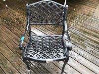 Photo of one black iron patio chair showing lattice seat and back with visible paint wear and peeling.