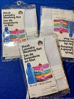 Photo showing the three packaged white mesh laundry washing nets with printed packaging labels indicating size and use.